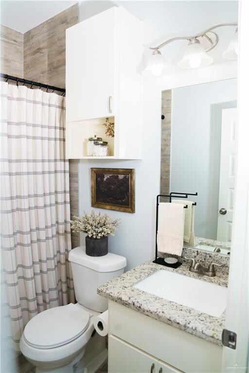 bathroom with walk in shower, vanity, and toilet