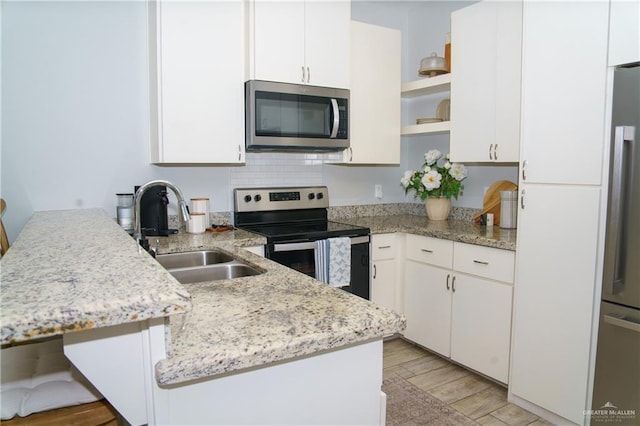 kitchen featuring white cabinetry, sink, stainless steel appliances, backsplash, and light hardwood / wood-style floors