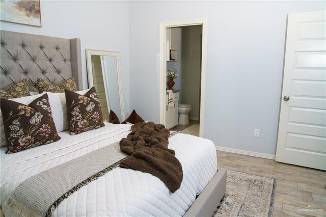 bedroom with light wood-type flooring and ensuite bath