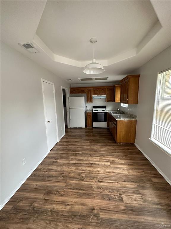 kitchen featuring a raised ceiling, sink, dark hardwood / wood-style floors, and white appliances