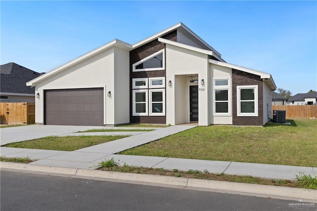 view of front of house featuring a garage, a front lawn, and central air condition unit