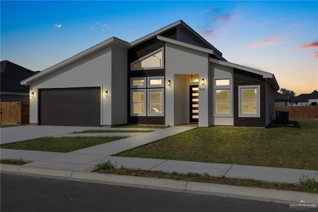 contemporary house with central AC, a garage, and a lawn