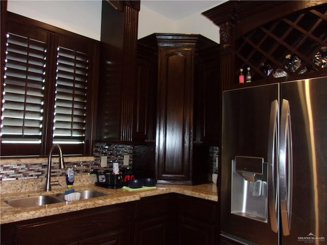 kitchen featuring light stone countertops, stainless steel refrigerator with ice dispenser, tasteful backsplash, and sink