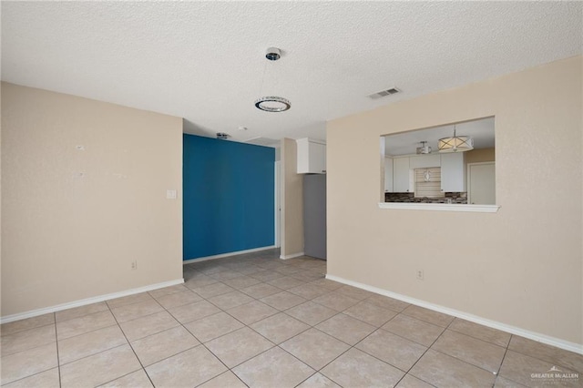 tiled spare room with a textured ceiling