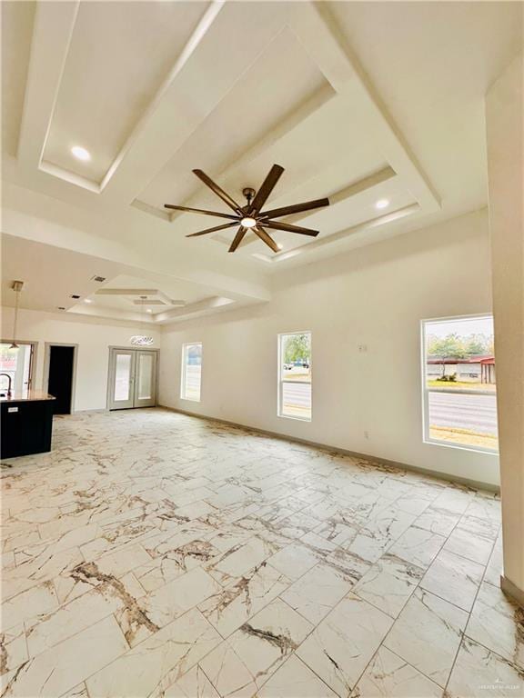 unfurnished living room featuring a raised ceiling, a wealth of natural light, and ceiling fan