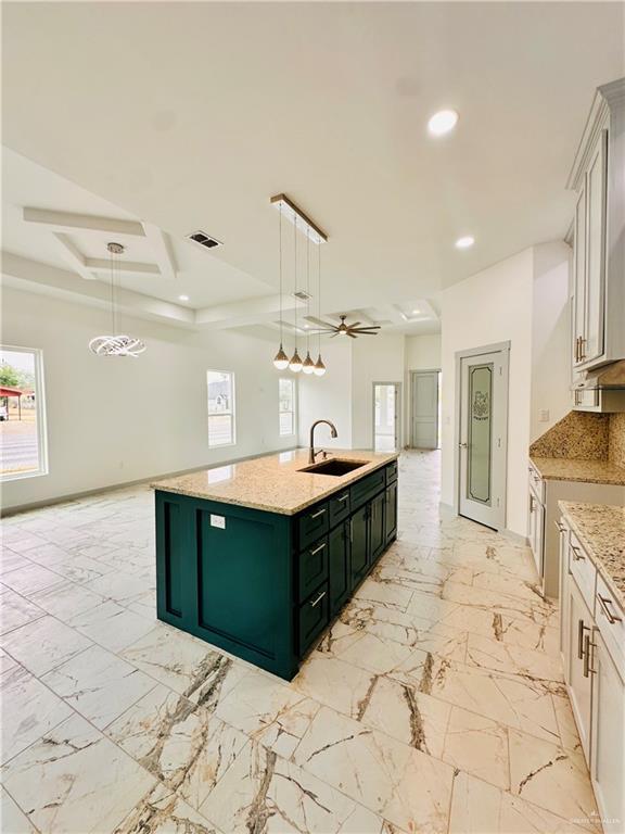 kitchen featuring white cabinets, pendant lighting, and an island with sink