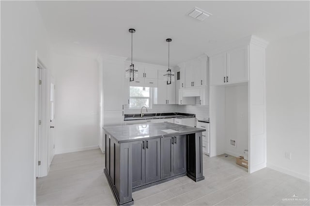 2005 Hacienda Cir, Harlingen, TX 78552 - kitchen with decorative light fixtures, visible vents, a sink, a kitchen island, and white cabinets