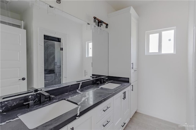 2005 Hacienda Cir, Harlingen, TX 78552 - bathroom featuring double vanity, a shower with door, baseboards, and a sink