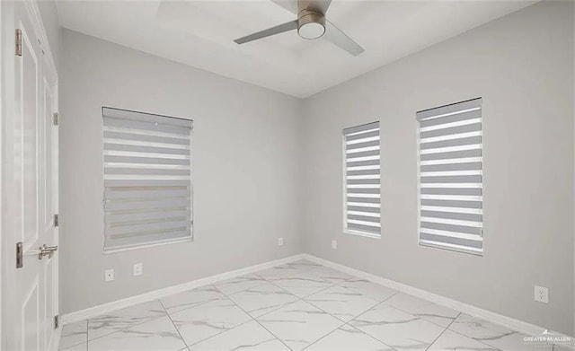 empty room with baseboards, a ceiling fan, and marble finish floor