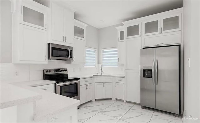kitchen featuring marble finish floor, a sink, white cabinetry, and stainless steel appliances