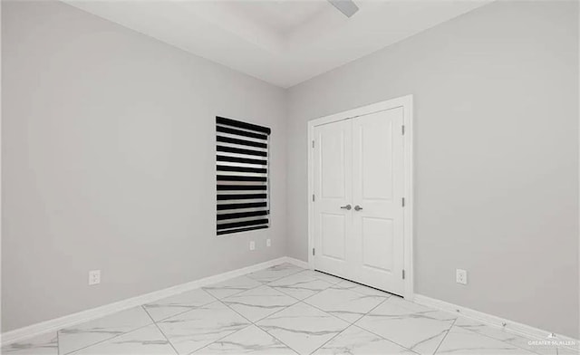unfurnished bedroom with a closet, marble finish floor, and baseboards