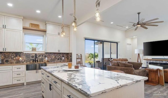 kitchen with decorative backsplash, sink, decorative light fixtures, white cabinets, and a center island