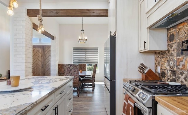 kitchen featuring light stone countertops, white cabinetry, hanging light fixtures, exhaust hood, and appliances with stainless steel finishes