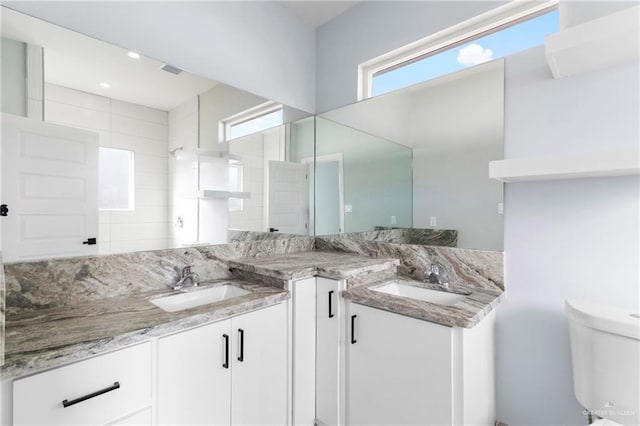 bathroom with vanity, tiled shower, and toilet