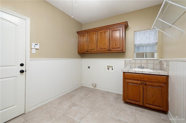 laundry area featuring hookup for an electric dryer, washer hookup, cabinets, sink, and light tile patterned floors