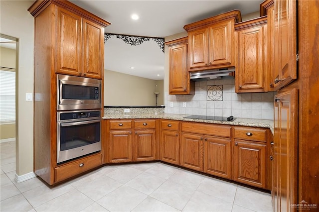 kitchen featuring decorative backsplash, light tile patterned flooring, light stone countertops, and appliances with stainless steel finishes