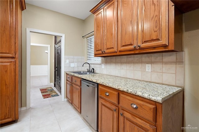 kitchen featuring dishwasher, sink, light tile patterned floors, tasteful backsplash, and light stone counters