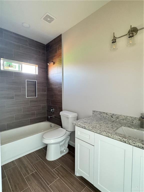 full bathroom featuring toilet, vanity, and tiled shower / bath combo