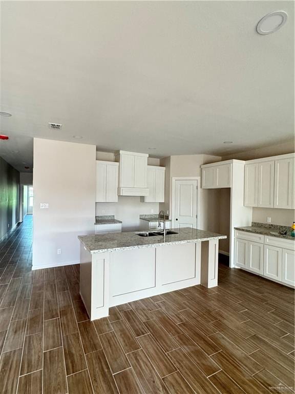 kitchen featuring white cabinets, dark hardwood / wood-style flooring, a kitchen island with sink, and sink