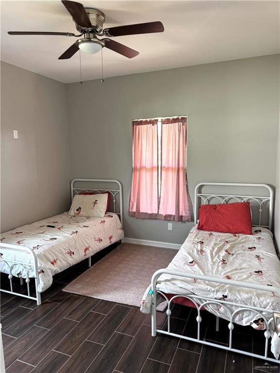 bedroom with a ceiling fan, wood finish floors, and baseboards