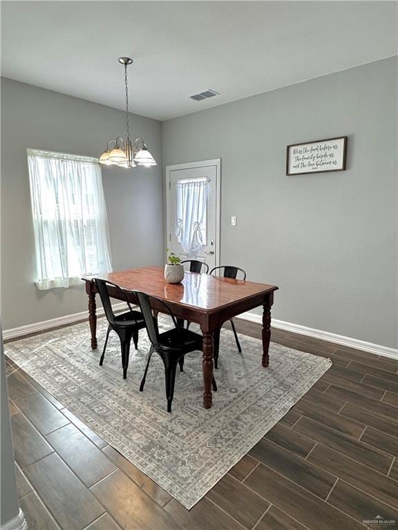 dining room with baseboards, visible vents, a notable chandelier, and wood finish floors