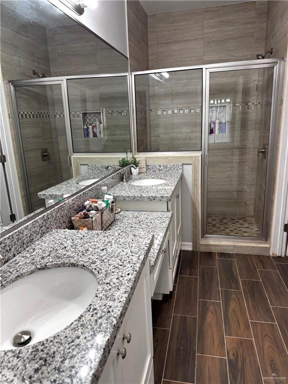 full bath featuring a stall shower, wood finish floors, and a sink