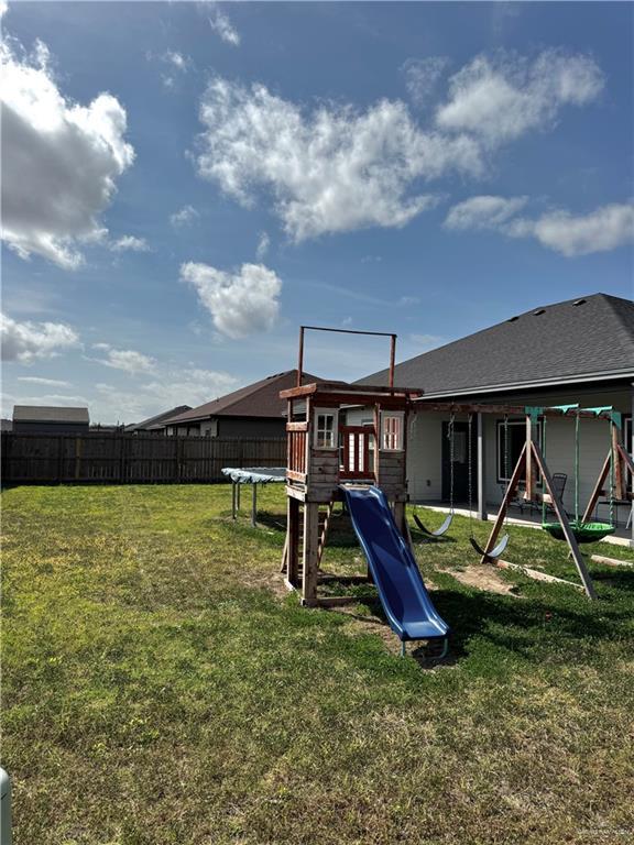 view of jungle gym featuring a trampoline, a lawn, and fence