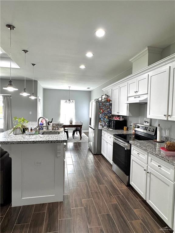 kitchen with appliances with stainless steel finishes, wood tiled floor, under cabinet range hood, white cabinetry, and a sink