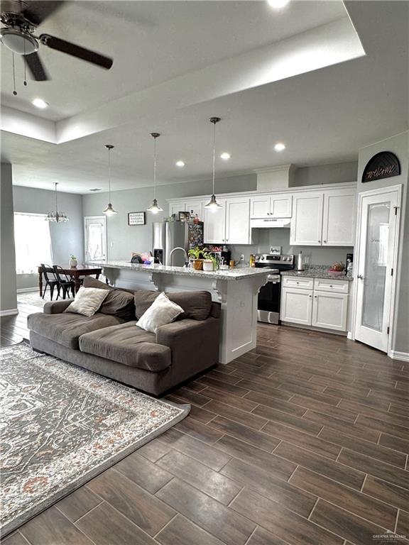 living room with a ceiling fan, wood finish floors, baseboards, and recessed lighting