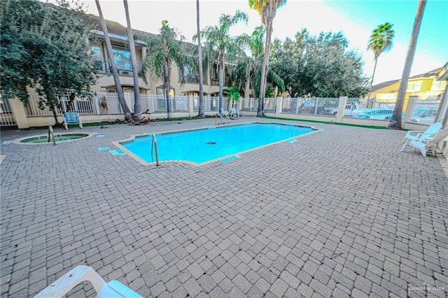 view of swimming pool featuring a patio area and a hot tub