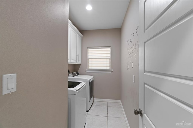 laundry room featuring washer and dryer, light tile patterned floors, and cabinets