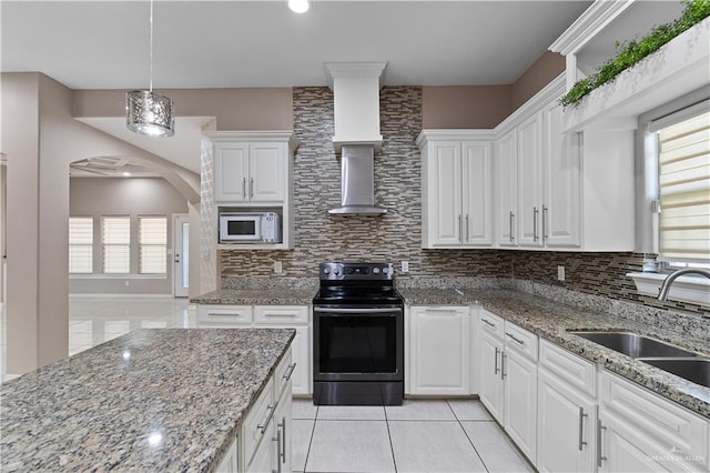 kitchen featuring stainless steel range with electric stovetop, wall chimney exhaust hood, white cabinets, and sink