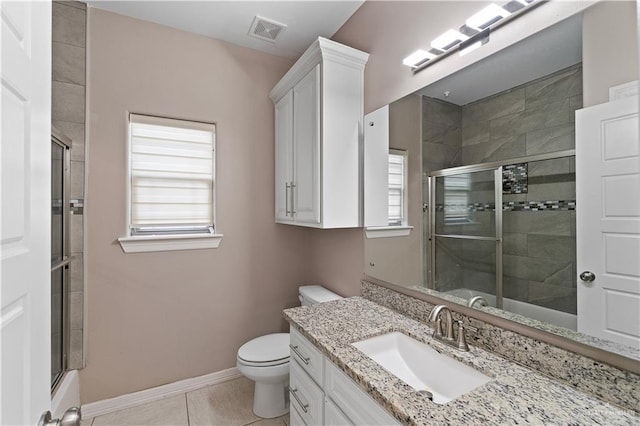 bathroom with tile patterned floors, a shower with door, vanity, and toilet