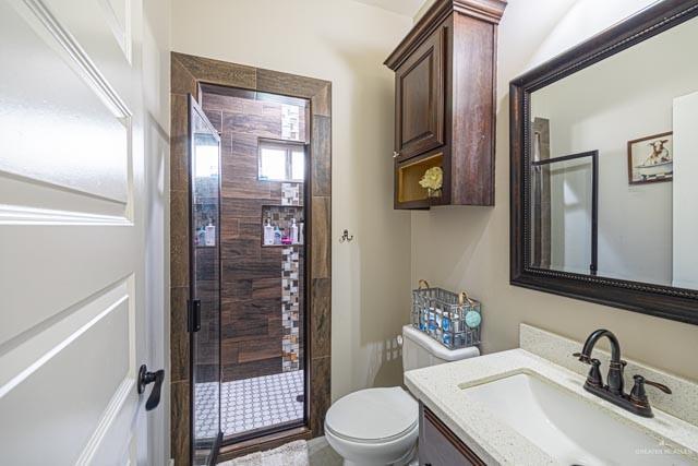 bathroom featuring vanity, a shower with shower door, and toilet