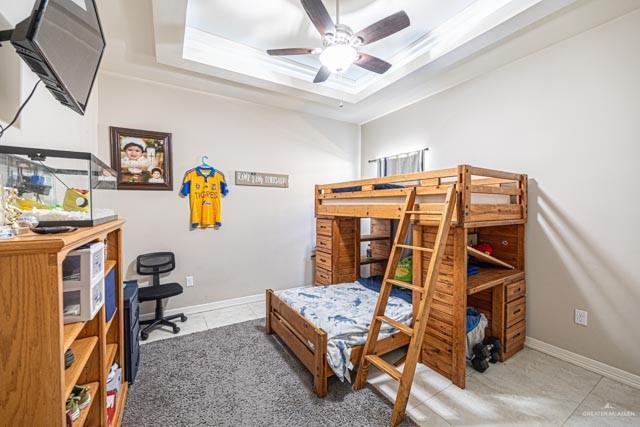 bedroom with a raised ceiling and light tile patterned flooring