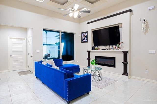 living room featuring beamed ceiling, ceiling fan, and coffered ceiling