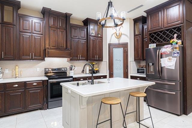 kitchen featuring backsplash, stainless steel appliances, and a center island with sink