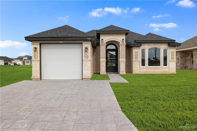 view of front of home with decorative driveway, a front yard, a shingled roof, a garage, and brick siding