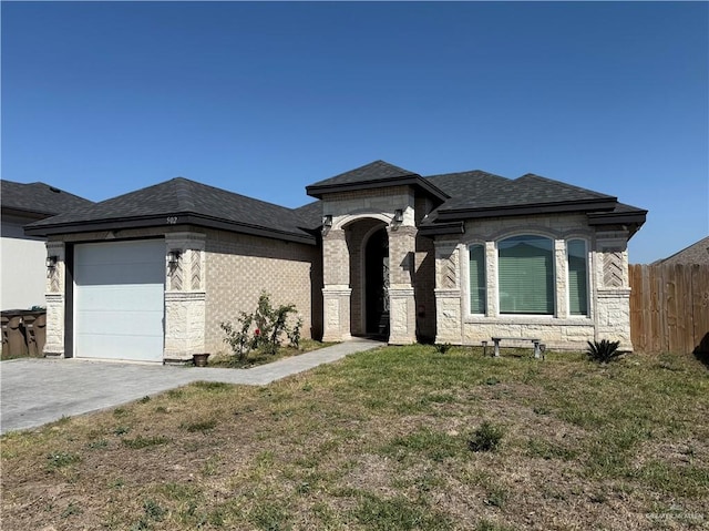 view of front of home with driveway, fence, a front yard, a shingled roof, and a garage