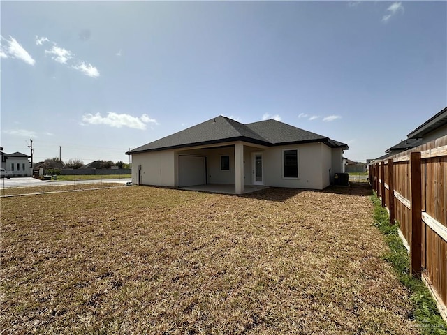 back of property featuring a yard, a patio area, fence, and central AC