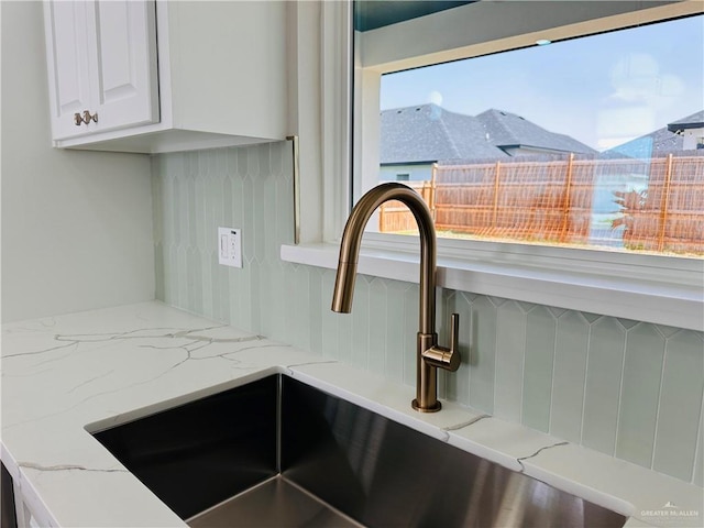 interior details featuring light stone countertops, white cabinets, and a sink