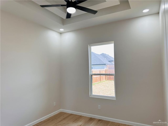 unfurnished room featuring recessed lighting, a raised ceiling, light wood-style floors, ceiling fan, and baseboards