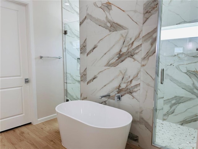 bathroom with wood finished floors, a soaking tub, and a marble finish shower