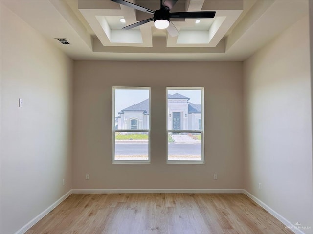 empty room with a ceiling fan, visible vents, light wood-style flooring, and baseboards