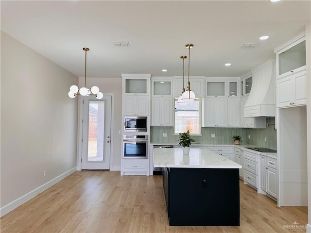 kitchen with stainless steel appliances, visible vents, custom exhaust hood, and tasteful backsplash