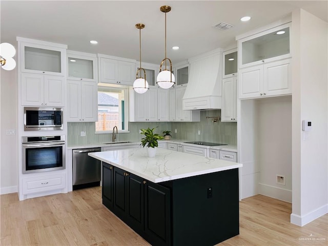 kitchen featuring stainless steel appliances, custom range hood, white cabinetry, a sink, and dark cabinetry