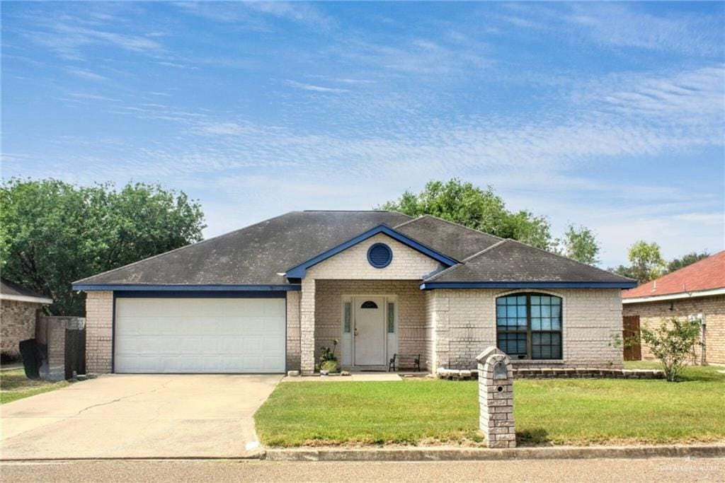 714 Maple St, Edinburg, TX 78539 - view of front of property featuring an attached garage, driveway, brick siding, and a front yard