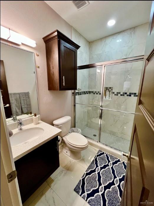 bathroom featuring vanity, toilet, and an enclosed shower