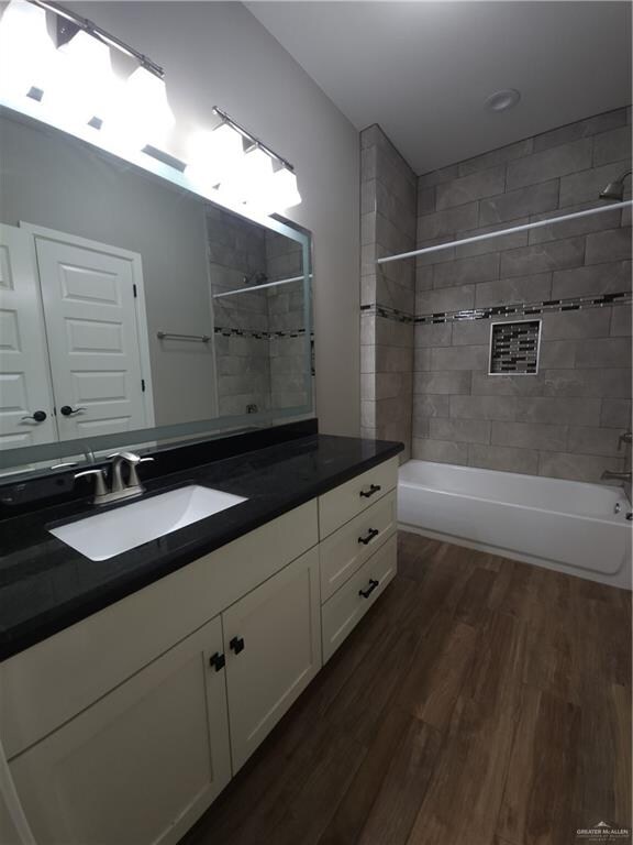 bathroom with tiled shower / bath combo, wood-type flooring, and vanity