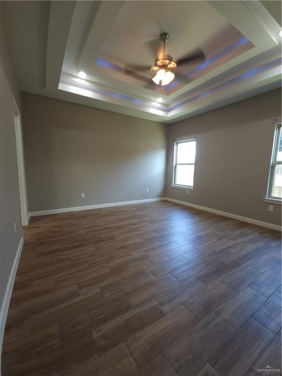 spare room with ceiling fan, dark hardwood / wood-style flooring, and a raised ceiling